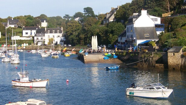 A harbor with boats, a building with a white facade, and a stone wall. - Detached house, facing south, av garage and enclosed garden, 350 m from the beach (Finistere (Clohars-Carnoët)