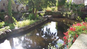 A narrow water channel with stone walls and greenery, surrounded by stone buildings with ivy and flowers. - Detached house, facing south, av garage and enclosed garden, 350 m from the beach (Finistere (Clohars-Carnoët)