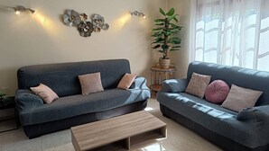 Una sala de estar con dos sofás azul oscuro, una mesa de centro de madera, decoración en la pared y una planta en maceta.
