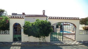 Propiedad privada con reja, piscina, techo de tejas y un pequeño jardín.