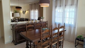 Un comedor con una mesa y sillas de madera, un candelabro y un espejo grande que refleja la habitación.