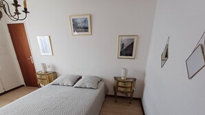 A bedroom with a bed, two bedside tables, a nightstand, and two framed pictures on the wall. - 2-Bedroom Apartment with Balcony in Sables-d'Olonne (Les Sables-d'Olonne)