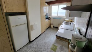 A compact kitchen with a refrigerator, stove, and sink. - 2-Bedroom Apartment with Balcony in Sables-d'Olonne (Les Sables-d'Olonne)