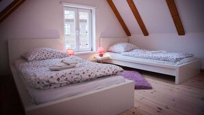 A bedroom with two beds, a window, and wooden beams.