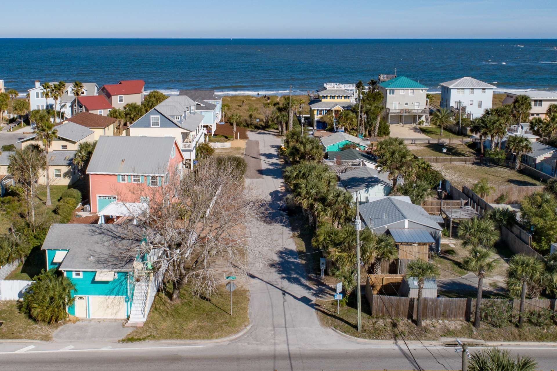 A coastal residential area with houses, a road, and a view of the ocean.