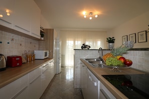 Cozinha moderna com armários brancos, micro-ondas, torradeira e uma fruteira sobre o balcão.