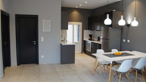 A modern kitchen with dark cabinetry, a central island, and a dining area with a table and chairs. - Luxury Apartment, Tranquility, Sea Views, Breeze (Agios Gordios, Kerkira)