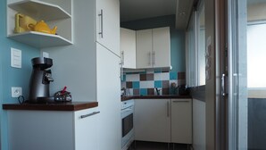 A compact kitchen with white cabinets, a coffee machine, and a tiled backsplash.