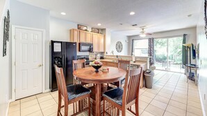 A modern kitchen with wooden cabinets, a central island, and a dining area with four chairs.