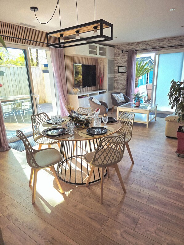 A dining area with a round table, chairs, and a television in the background.
