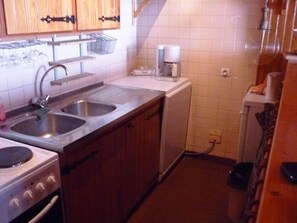 A compact kitchen with a double sink, a coffee maker, and a small refrigerator.