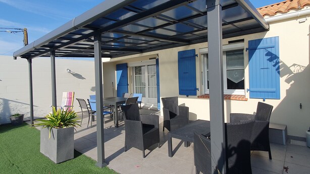 Ein überdachter Patio-Bereich mit Gartenmöbeln und einer Pergola.