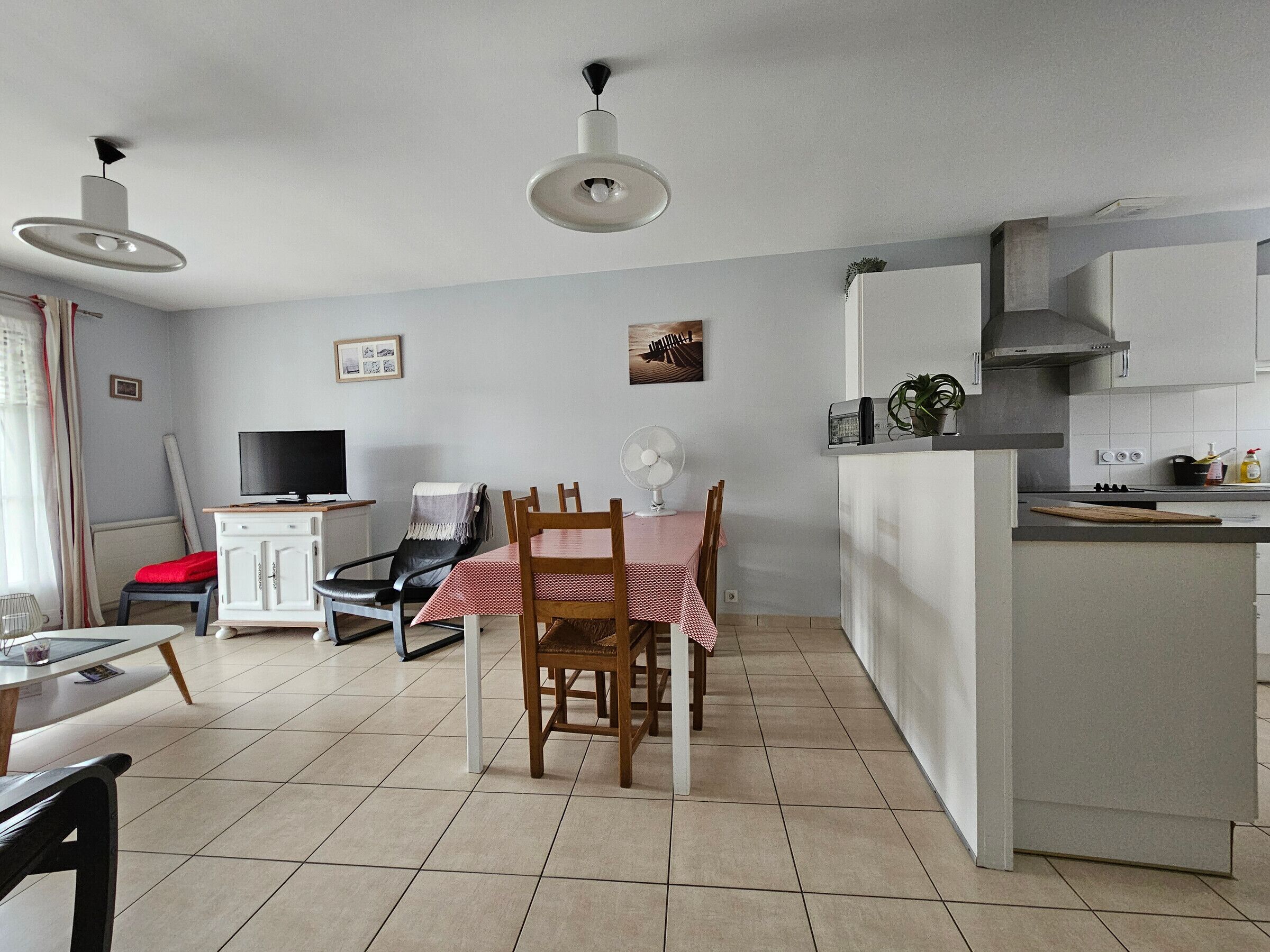 Un espace de vie compact comprenant un coin repas, une kitchenette et un téléviseur.