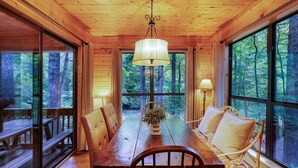 Ein Essbereich aus Holz mit einem Tisch, Stühlen und einer hängenden Leuchte.