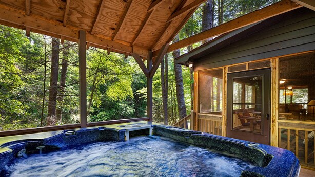 Ein Whirlpool mit Holzterrasse und Blick auf den Wald.