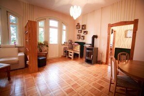 Una sala de estar acogedora con chimenea, piso de madera, un sofá, una mesa de comedor y una estantería.