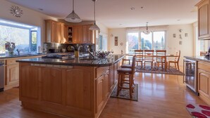 A spacious kitchen with wooden cabinets, a large island, and a dining area with a table and chairs. - Perfect For Large Family Get Aways Or Your Gorgeous Ranch Style Wedding. (Arroyo Grande)