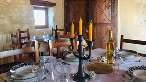 Una mesa de comedor rústica con platos, vasos, un candelabro y una botella.
