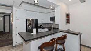 Una cocina moderna con una isla central, electrodomésticos de acero inoxidable y taburetes de bar.