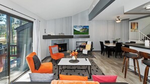 Una sala de estar moderna con chimenea, papel tapiz a rayas y una zona de comedor con una mesa grande y sillas.