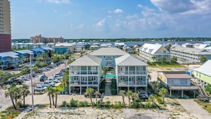 Een kusthotel met meerdere gebouwen, een parkeerplaats en een strand op de achtergrond.