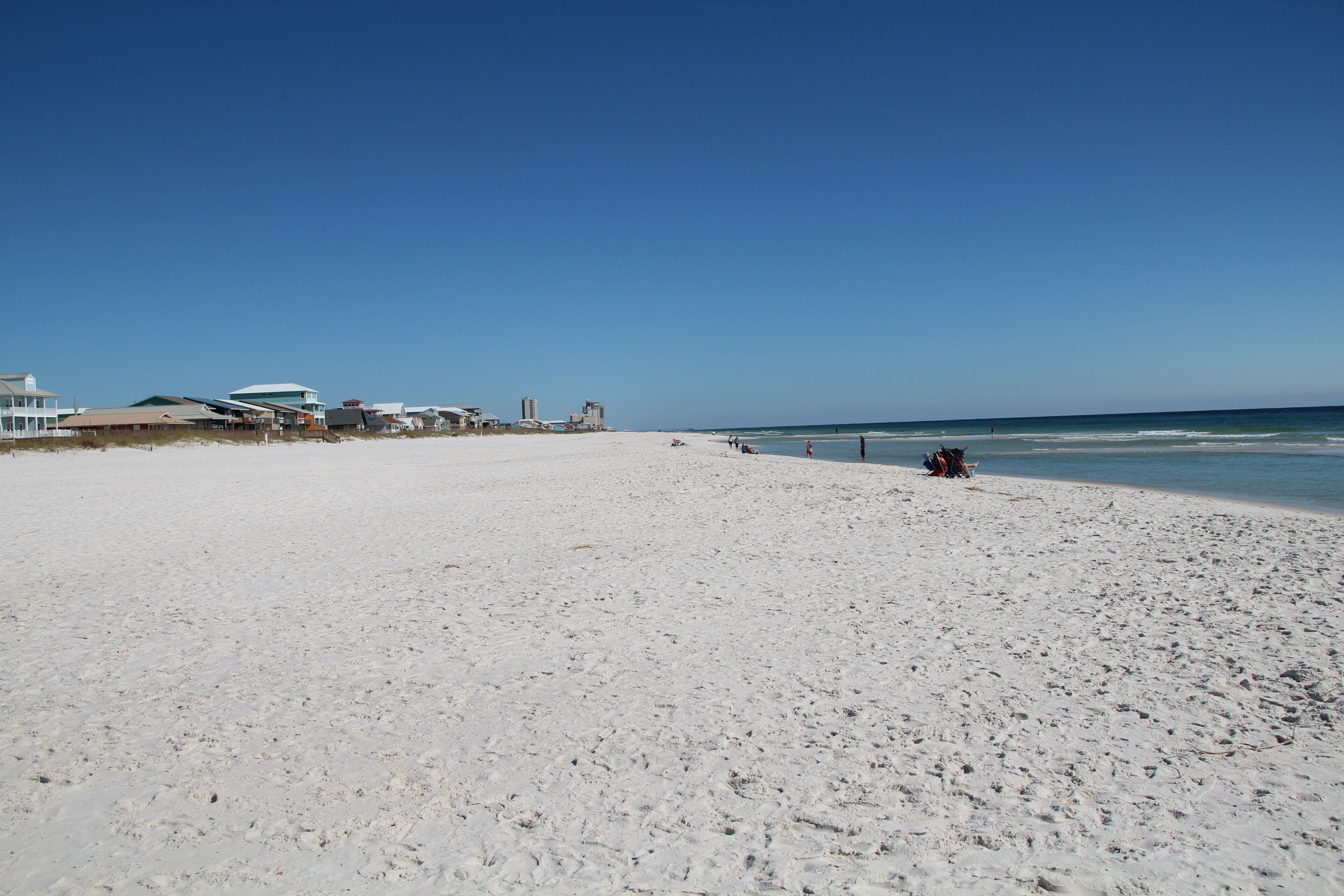 Ein weiter Sandstrand mit blauem, wolkenlosem Himmel.