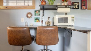 A kitchen with two stools, a microwave, and various decorative items on the counter.
