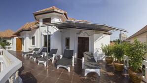 A modern villa with a tiled patio, outdoor seating, and potted plants. - RATANA VILLA - PATTAYA HOLIDAY HOUSE - WALKING STREET (Muang Pattaya)