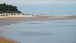 A beach with a row of beach huts and a sandy shoreline. - Avocet Apartment, Wells-next-the-Sea, Norfolk (Wells-Next-The-Sea)