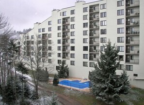 A multi-story residential building with balconies, a swimming pool, and surrounding trees. - March Deals - Silvercreek Lodge! 2BDR/2Bath. Ski In/Out, Wifi, Pool, Hot Tub (snowshoe)