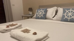 Una cama bien hecha con toallas, una mesita con una lámpara y una mesita de noche con lámpara.