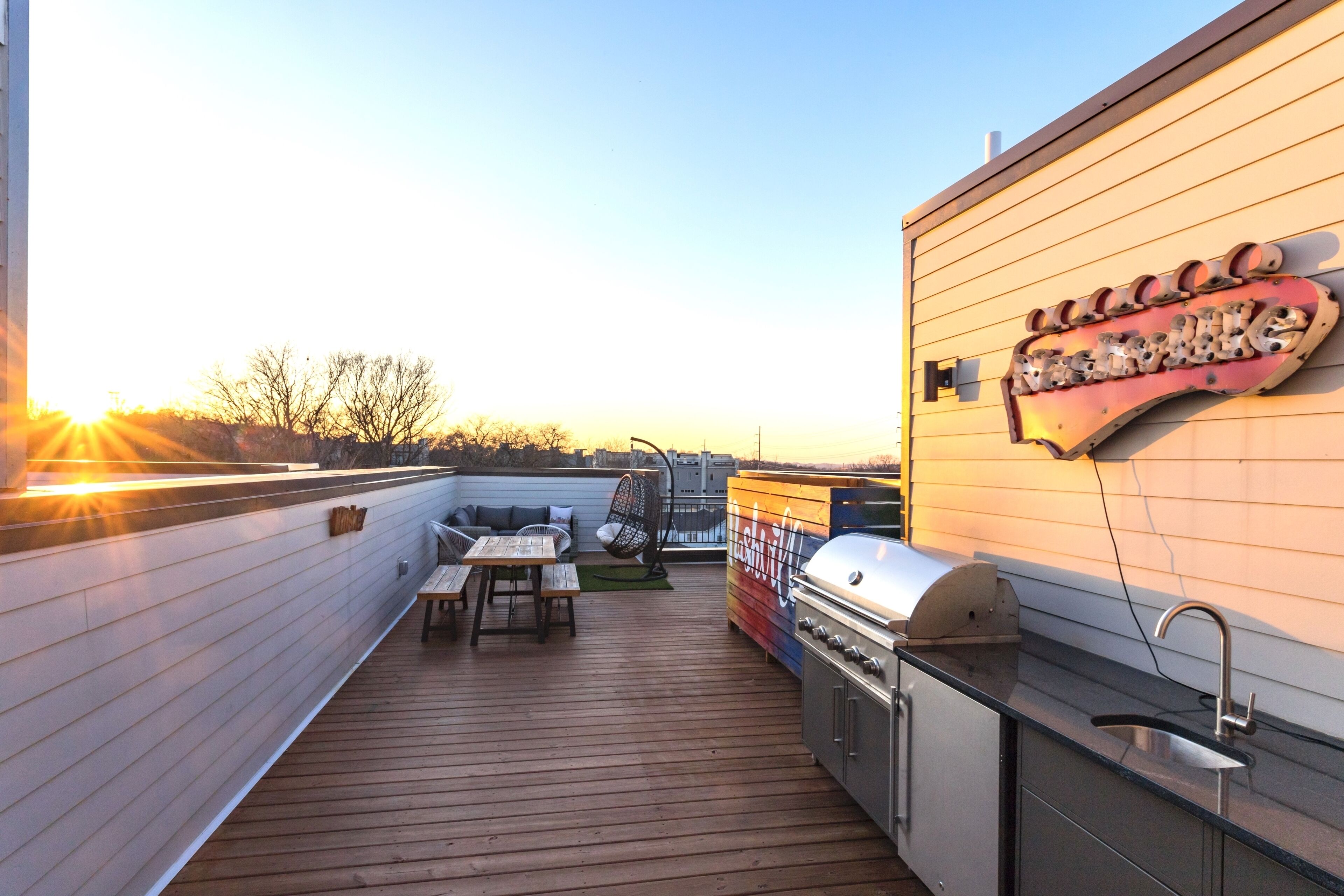 Eine Dachterrasse mit Grill, Esstisch und Ventilator.