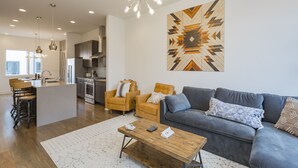 A modern living room with a grey sofa, wooden coffee table, and a patterned wall hanging. - Rooftop+Downtown close*  Nashville mural* (Nashville)