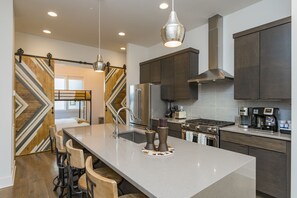 A modern kitchen with a large island, stainless steel appliances, and a stylish pendant light. - Rooftop+Downtown close* Nashville mural* (Nashville)