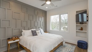 A bedroom with a bed, a ceiling fan, a window, and a TV on a shelf. - Rooftop+Downtown close*  Nashville mural* (Nashville)
