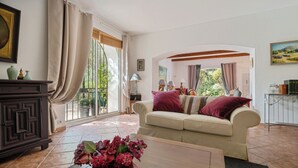Un salon avec un canapé beige, un meuble en bois foncé et un vase de fleurs posé sur une table en bois.