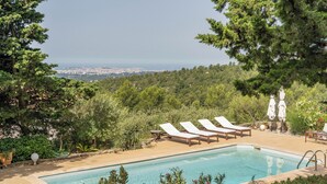 Une piscine avec des chaises longues et une vue sur le paysage urbain.