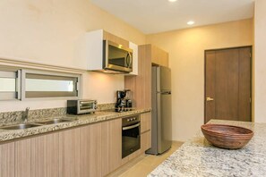 A modern kitchen with a built-in microwave, a stainless steel refrigerator, and a coffee maker on the countertop.