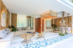 A modern living room with a sofa set, two wicker chairs, a coffee table, and a patterned floor.