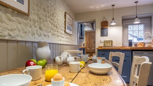 A kitchen with a wooden table set for breakfast, including bowls, eggs, and apples.