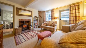 A cozy living room with a fireplace, a sofa, a coffee table, and a bookshelf.