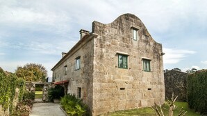 A stone building with a curved roof, a small porch, and a garden with plants and a pathway. - Abadía Apartment, Rectoral of Areas (Tuy)
