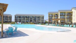 Un hôtel doté d’une piscine, de chaises longues et d’un espace salon abrité.