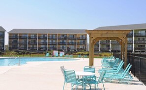 A pool area with lounge chairs and a wooden pergola. - The Haven - Oceanfront Surf Condo! Community Pool, Sleeps 4 (Surf City)