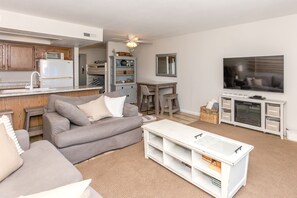 Ein Wohnzimmer mit grauem Sofa, einem weißen Couchtisch und einem Fernseher an der Wand.