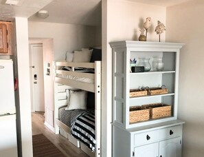 Ein Schlafzimmer mit einem Etagenbett, einer weißen Kommode mit Körben und einem weißen Schrank mit Dekoration.