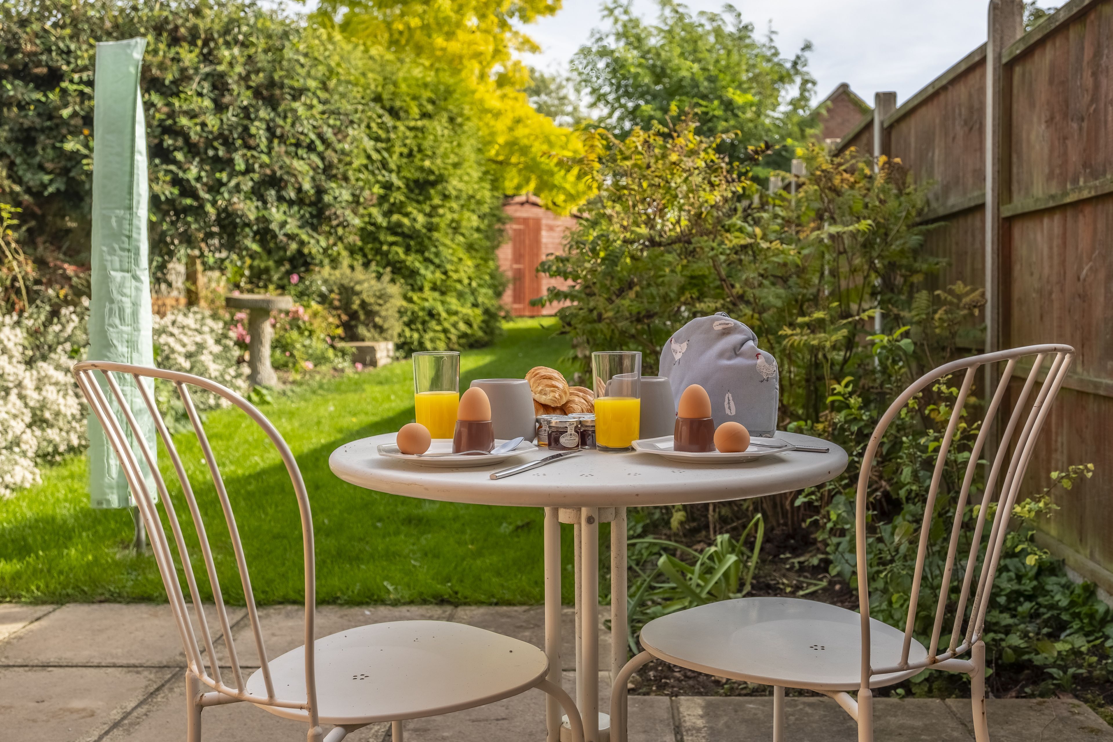 Een ronde tafel met twee stoelen in een tuin.