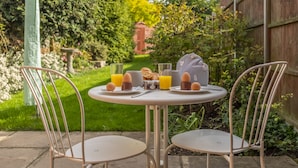 A round table with two chairs in a garden setting.