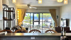 A kitchen area with a counter, chairs, and a view of the beach. - Updated/Beachfront/180 Sunset View/Dock/Dive Shop/Pool/Restaurants (Kralendijk)