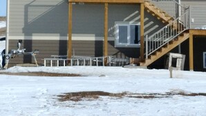 A two-story house with a covered porch, a staircase, and a large window on the upper floor. -  30 Mins to Waterton Gate! Relax & Enjoy the View of Chief Mountain & Sunsets (CARDSTON)
